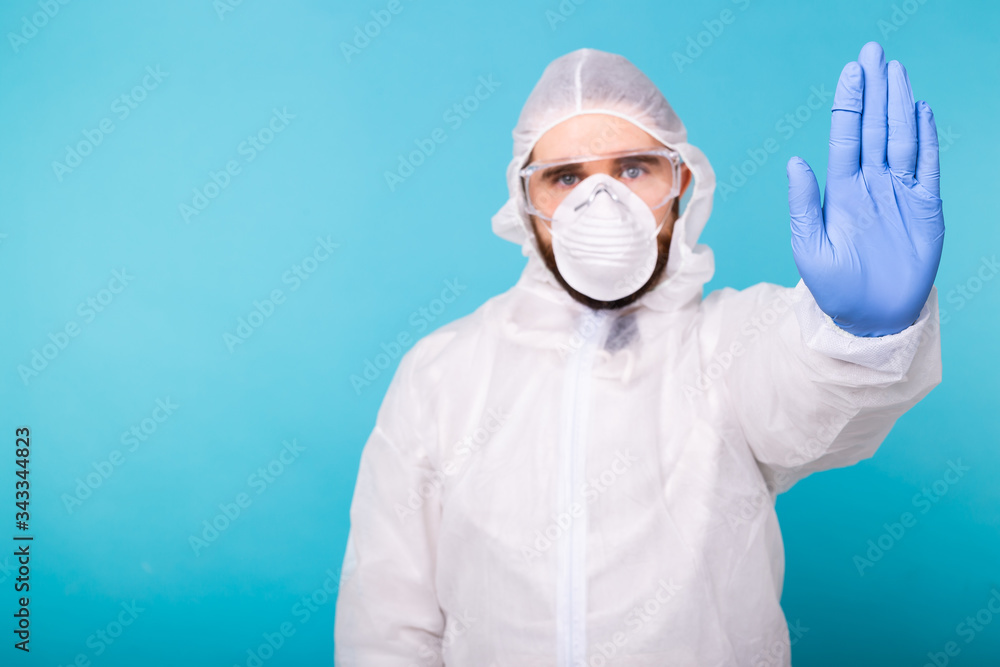 Doctor or lab scientist wearing biohazard protective suit hand gesturing Stop Coronavirus COVID-19 disease global pandemic outbreak. Restrictive no entry, quarantine order. Doctor or lab scientist wearing biohazard protective suit hand gesturing Stop Coronavirus COVID-19 disease global pandemic outbreak. Restrictive no entry, quarantine order.