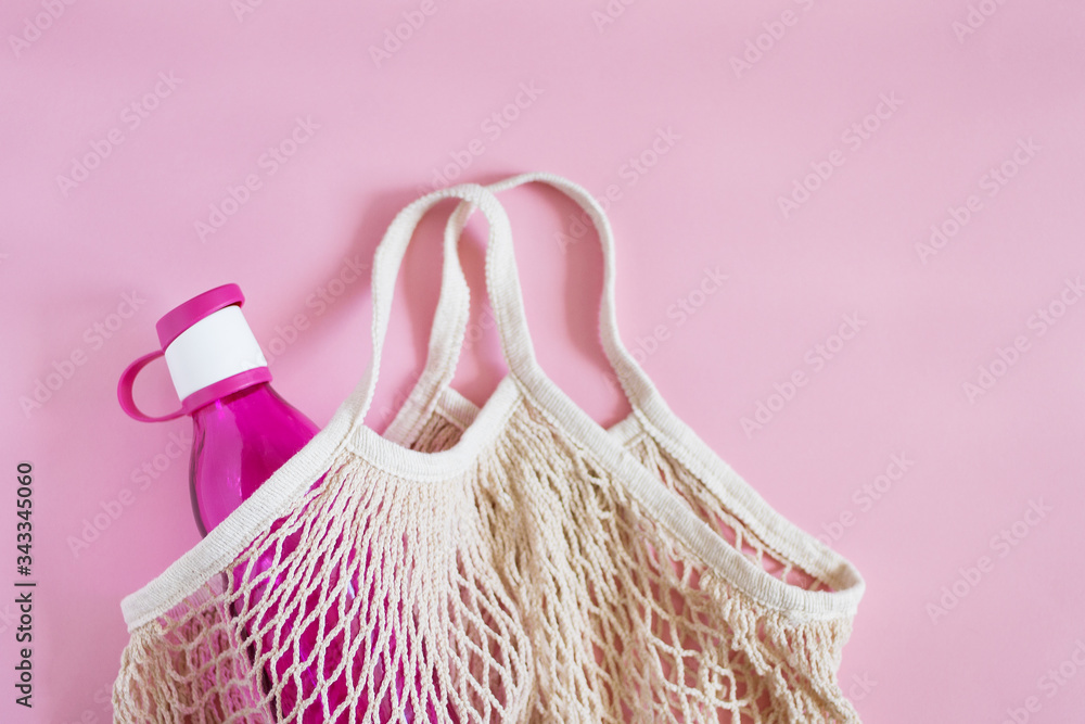 Fototapeta premium Reusable shopping bag with bottle on color background.