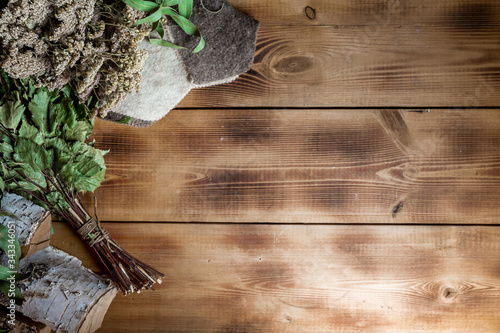 Various sauna accessories in a wooden Finnish sauna or Russian bathhouse with traditional sauna accessories: birch broom, felt hat,pumice, birch wood medicinal herbs. Relax concept. Copy space