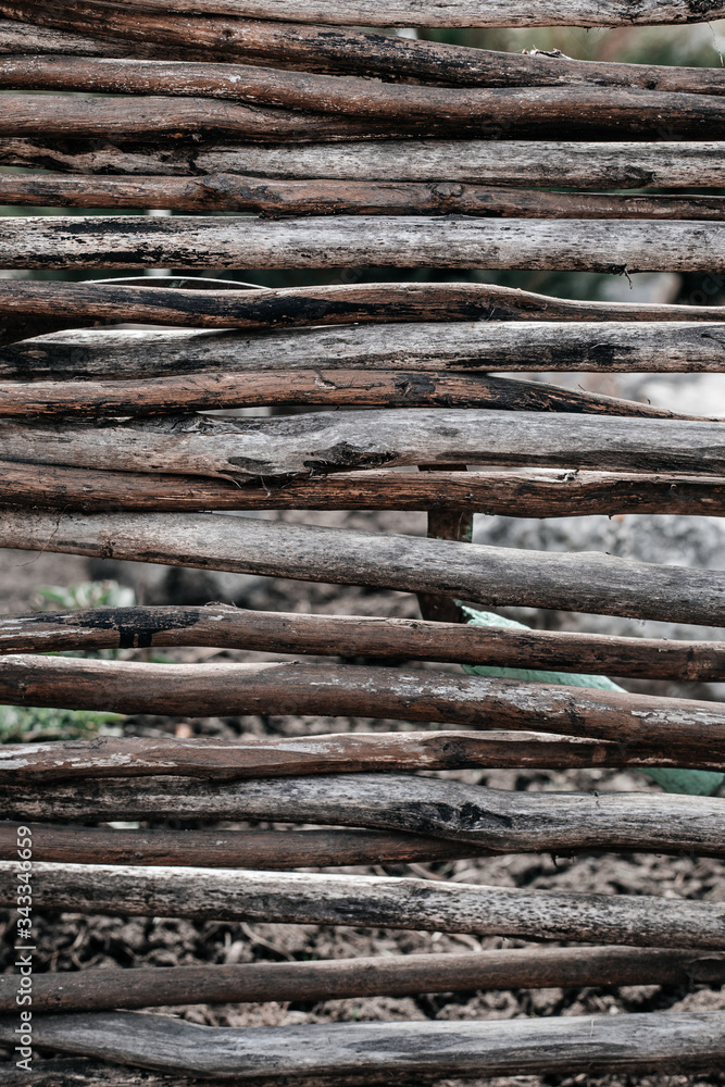 The texture of a beautiful wicker fence made of dry branches that lie tightly together. Wooden background The texture of a beautiful wicker fence made of dry branches that lie tightly together. Wooden background