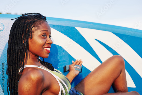 Canvas Print Attractive young Black woman with fit body resting after surfing in sea