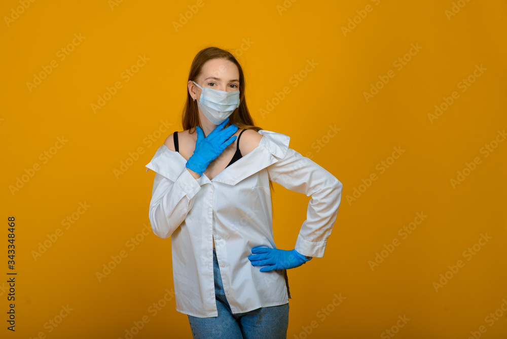 The caucasian girl in blue colored protective face mask. The girl looking at camera. Portrait shot over yellow background. virus and pollution protection concept. The caucasian girl in blue colored protective face mask. The girl looking at camera. Portrait shot over yellow background. virus and pollution protection concept.