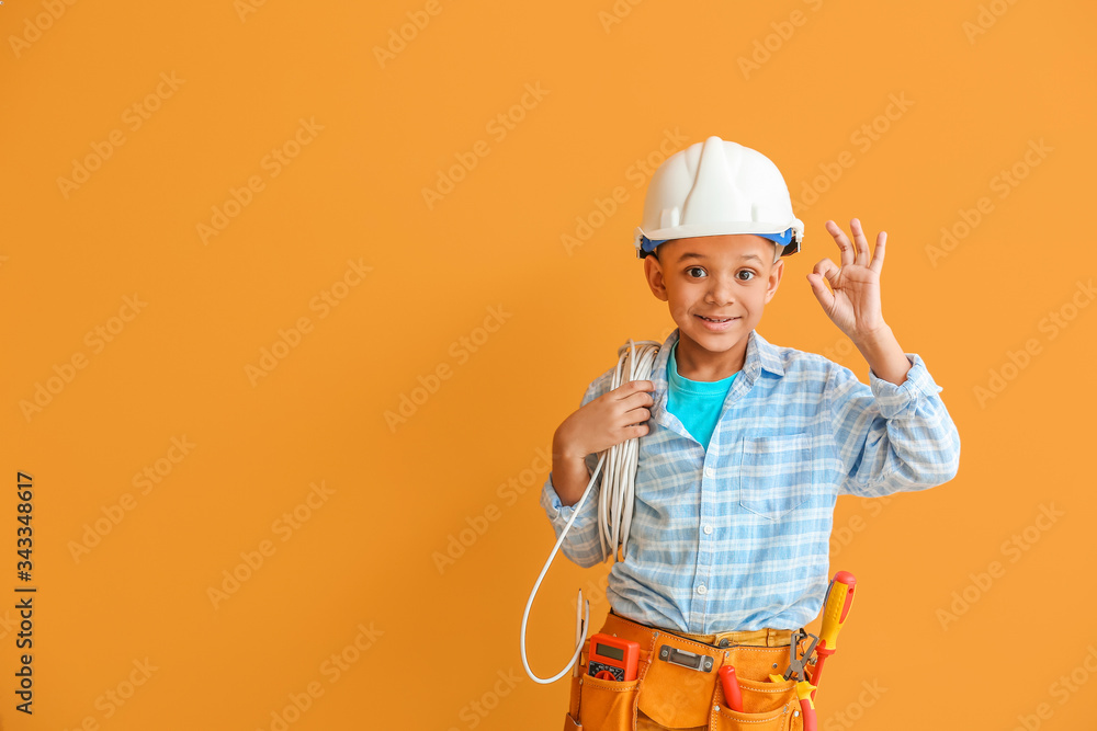 Little African-American electrician showing OK on color background