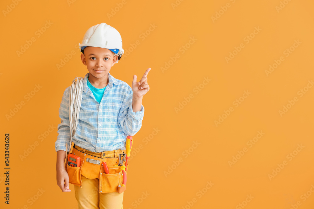 Little African-American electrician pointing at something on color background Little African-American electrician pointing at something on color background