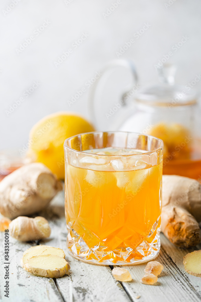 Yellow drink with ginger, lemon and ice in a glass, refreshing homemade ginger lemonade or ale on white background Yellow drink with ginger, lemon and ice in a glass, refreshing homemade ginger lemonade or ale on white background