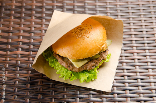 Cheeseburger with cutlet, cheese and lettuce in a paper bag. fast food takeaway