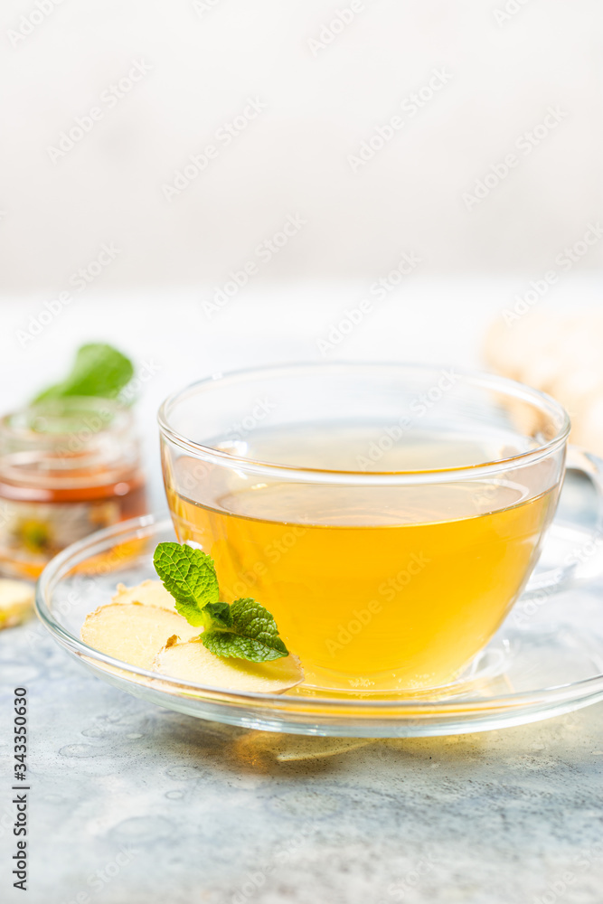 Ginger tea in a glass cup with lemon and mint on light background Ginger tea in a glass cup with lemon and mint on light background