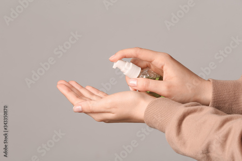 Woman with sanitizer on grey background