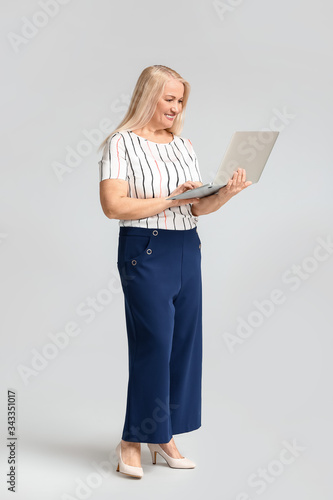 Portrait of mature businesswoman with laptop on light background