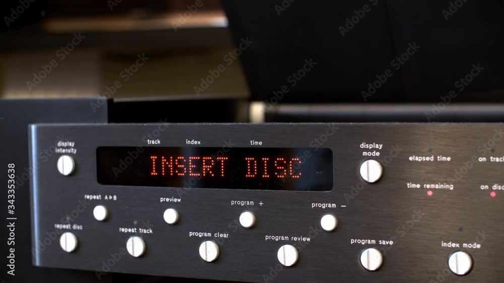 Male hands inserting CD disk in music player. Close up black digital player reading disk. Video player starting counter on display Male hands inserting CD disk in music player. Close up black digital player reading disk. Video player starting counter on display