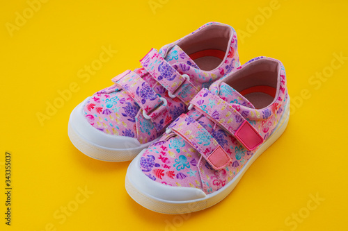 Kids colorful casual shoes isolated on yellow background