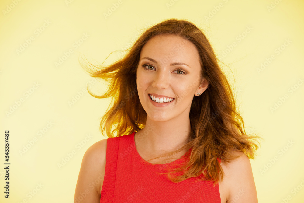 Beautiful young haapy woman in vibrant dre dress over yellow background Beautiful young haapy woman in vibrant dre dress over yellow background
