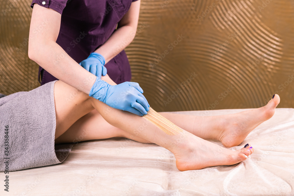 Sugaring processing, epilation with liquate sugar at legs, close-up. Beauty and cosmetology concept.