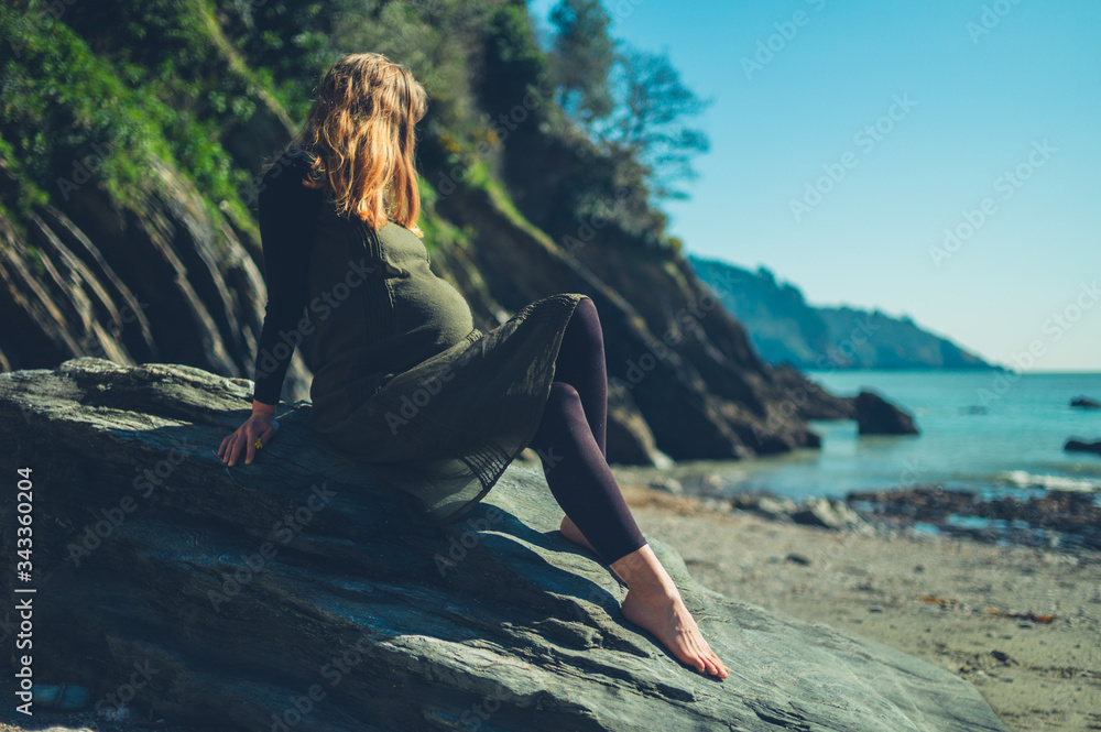 Pregnant woman sitting on rock by the sea Pregnant woman sitting on rock by the sea