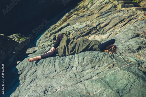 Pregnant woman lying on a rock in the sun