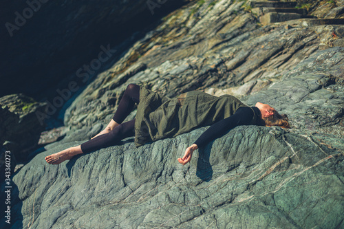 Pregnant woman lying on a rock in the sun