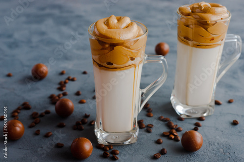 Trendy, trendy Dalgon coffee drink made from vegetable or regular milk with coffee foam. Two glasses stand on a black background and next to the candy photo