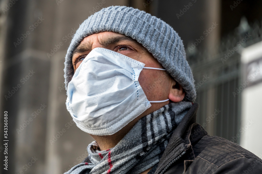 Disease outbreak, COVID-19 (Coronavirus SARS-CoV-2) pandemic. Headshot of a man covering his face with a medical mask to protect his nose and mouth posing outdoors Disease outbreak, COVID-19 (Coronavirus SARS-CoV-2) pandemic. Headshot of a man covering his face with a medical mask to protect his nose and mouth posing outdoors