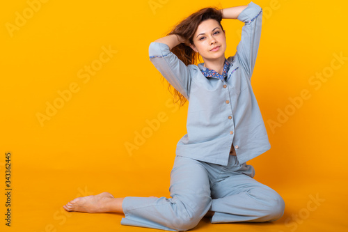 Young girl posing in pajamas on yellow background. Relax good mood, lifestyle and sleepwear concept. © satura_