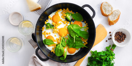 Healthy breakfast table with fry pan eggs with spinach on white background top view