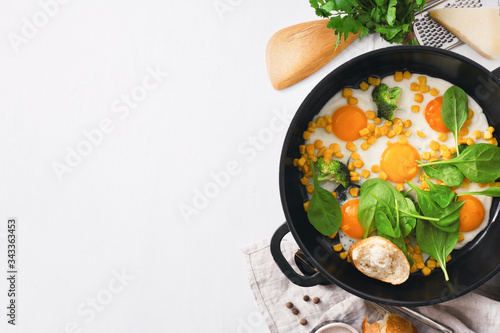 Healthy breakfast table with fry pan eggs with spinach on white background with copy space top view photo