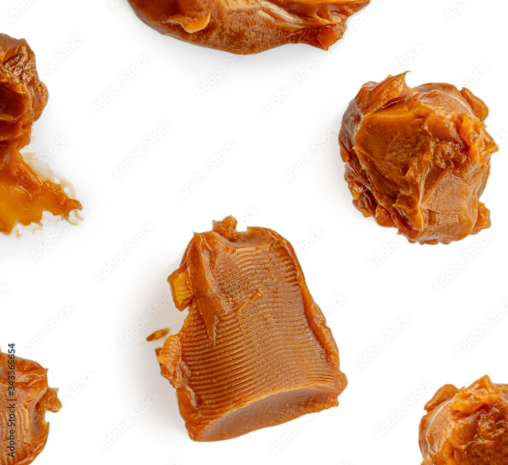 Soft melted caramel Pattern. Golden Butterscotch toffee candy isolated on a white background Macro. Soft melted caramel Pattern. Golden Butterscotch toffee candy isolated on a white background Macro.