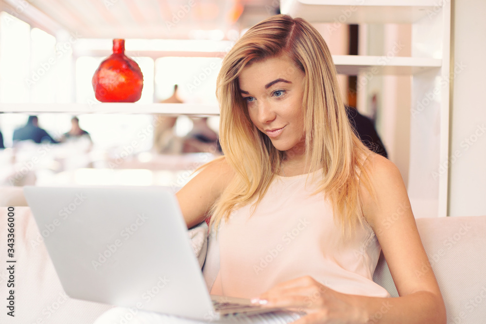 a beautiful young businesswoman is working with interest on a laptop in a cosy cafe in the morning a beautiful young businesswoman is working with interest on a laptop in a cosy cafe in the morning