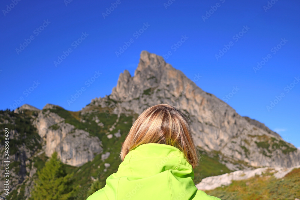 A girl looks at the Dolomites in Italy. Back view. Selective focus.