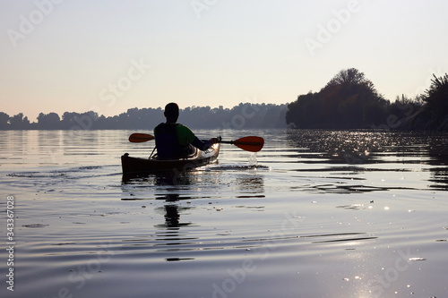 Silhouette of a lone man kayaking at the evening near the shorelines in Danube river