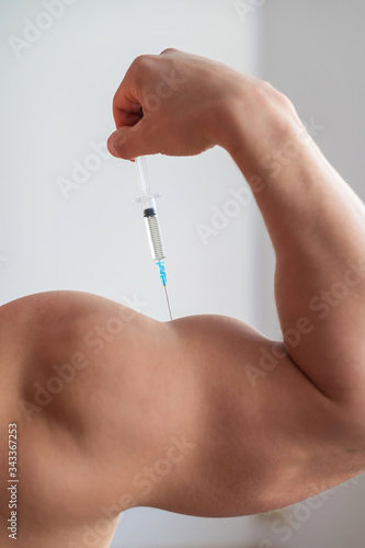 Close-up of male biceps. Unrecognizable male bodybuilder puts himself an injection of testosterone. Faceless athlete takes growth hormone. Vertical .