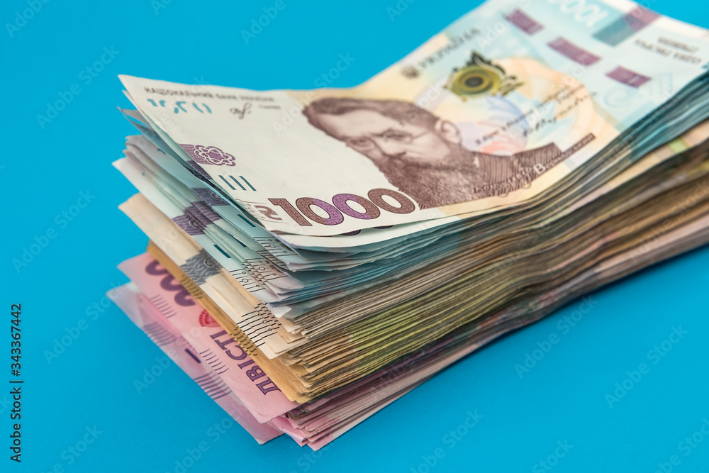 Ukrainian hryvnia money new bills 1000 and 500 isolated on blue. Stack of money. Ukrainian hryvnia money new bills 1000 and 500 isolated on blue. Stack of money.