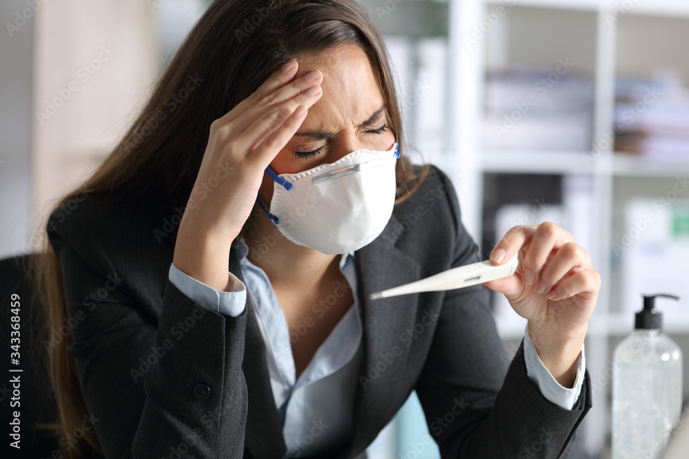 Executive with headache holding thermometer wearing mask Executive with headache holding thermometer wearing mask