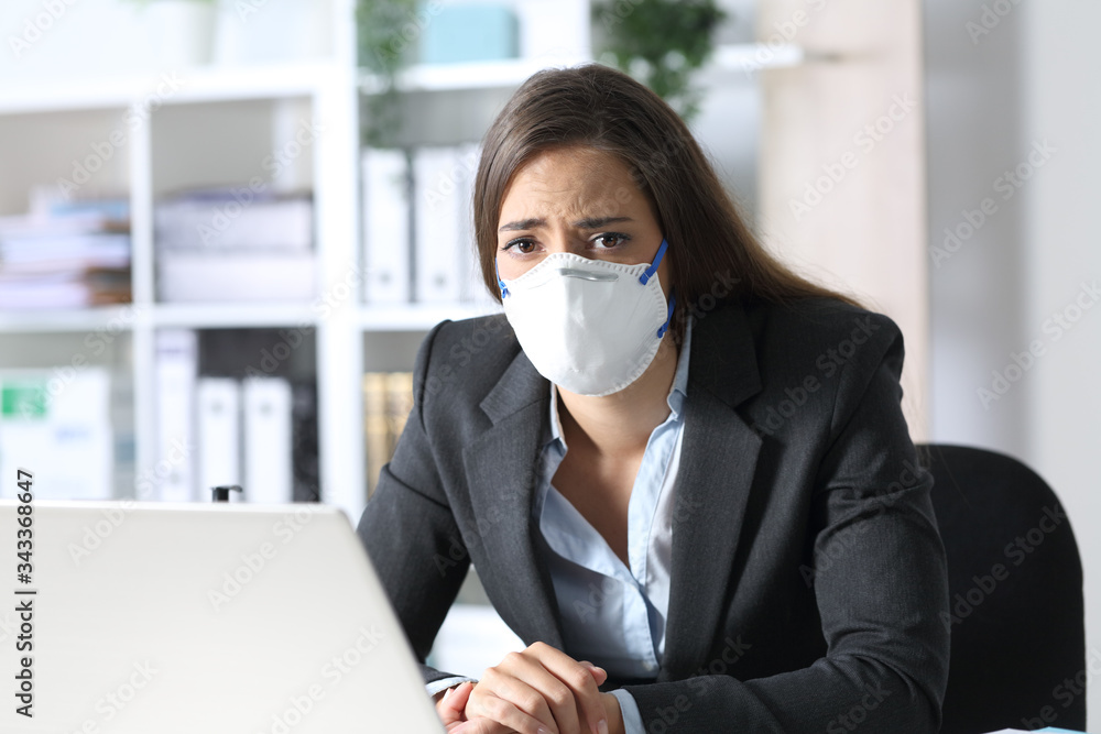 Sad executive wearing mask looking at camera at the office Sad executive wearing mask looking at camera at the office