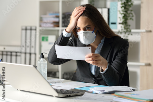 Surprised executive with mask looking at receipt at office