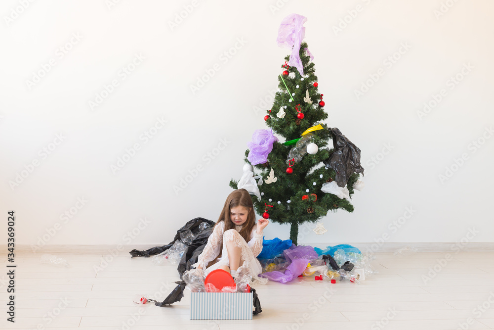 Environmental protection and pollution concept. Surprised child carrier box with plastic trash over christmas tree background. Environmental protection and pollution concept. Surprised child carrier box with plastic trash over christmas tree background.