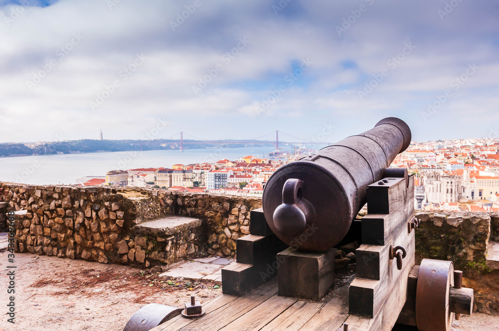 Ancient bronze cannon of Saint George castle and panorama of Lisbon in the background in Portugal