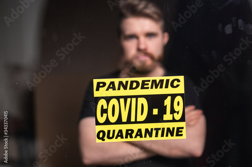 Coronavirus, quarantine, covid-19 and pandemic concept. Sad and sick man of corona virus looking through the window. Stay at home.