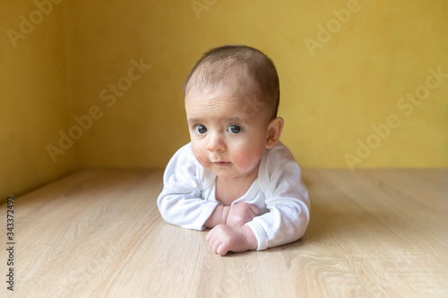 Newborn baby. A little boy in white bodysuit . Beautiful portrait of a toddler. Big-eyed baby. Remote education. Distance learninig 