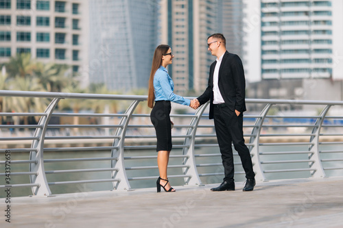 Businessman and businesswomen shaking hands outside office