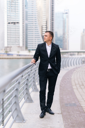 Handsome young business man standing agains skyscrapers outdoors
