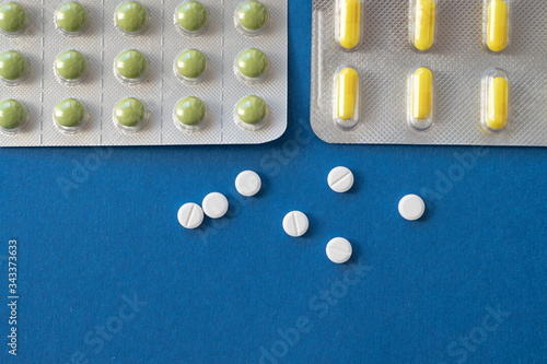 close-up of white,green,yellow pills in a package on a blue background