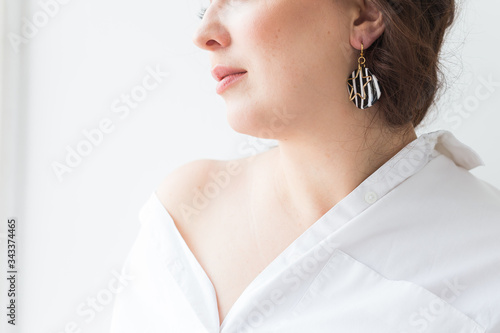 Close-up of fashion shoot of young brunette woman with elegant hairstyle in white studio. Trendy style concept.