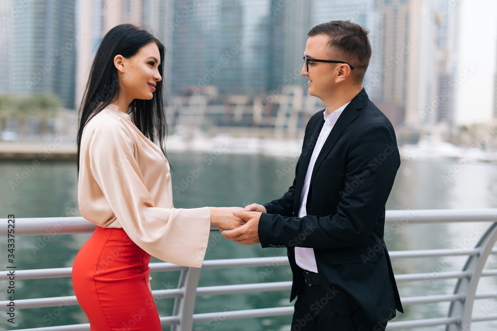 An attractive business man and woman team shaking hands outdoors on skyscrapers An attractive business man and woman team shaking hands outdoors on skyscrapers