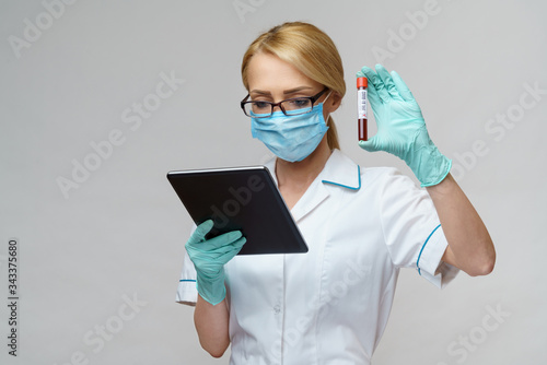medical doctor nurse woman wearing protective mask and gloves - holding virus blood test and tablet pc