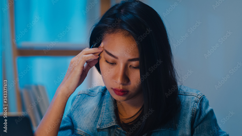 Millennial young Chinese businesswoman working late night stress out with project research problem on laptop in living room at modern home. Asia people occupational burnout syndrome concept. Millennial young Chinese businesswoman working late night stress out with project research problem on laptop in living room at modern home. Asia people occupational burnout syndrome concept.