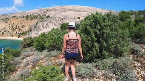 smiling woman walk on the rocky hills of Krk Island. View Adriatic sea. Croatia