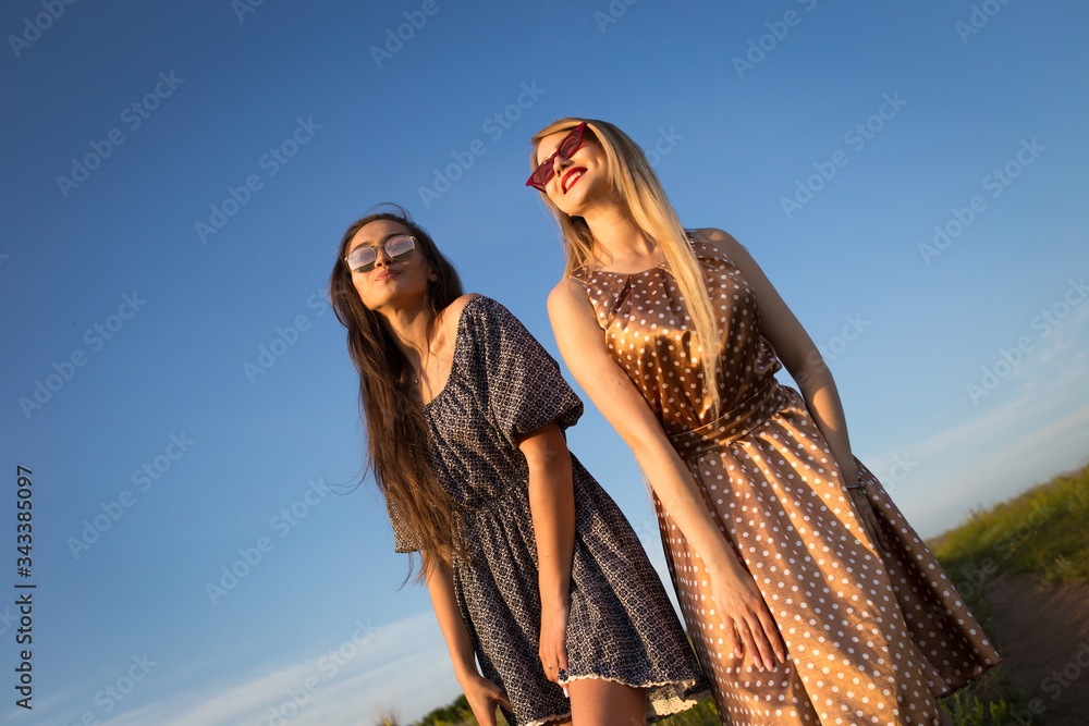 Young women holding hands on the field. Summer sunset sun.