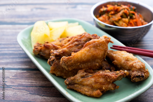 Fried chicken wings with Korean pickle kimchi on a wooden table