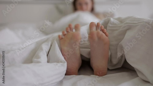 Female feet moving in a white bed