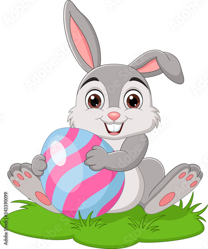 Cartoon little rabbit holding easter egg in the grass